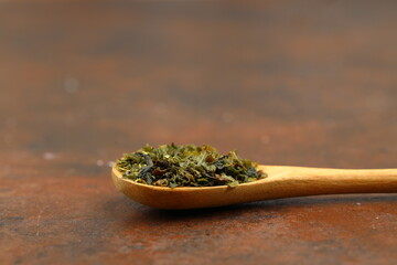 Green  tea with herbs in wooden spoons on a wooden board