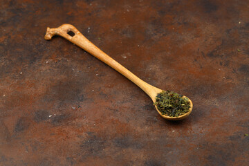 Green  tea with herbs in wooden spoons on a wooden board