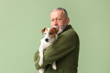 Senior man with cute dog on green background