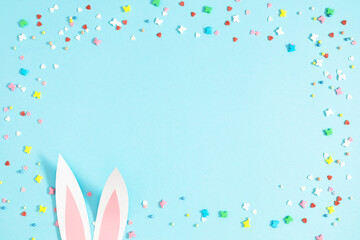 Easter holiday composition. Easter decorations, funny bunny ears , colorful sugar candies on isolated pastel blue background. Easter concept. Flat lay, top view, copy space 