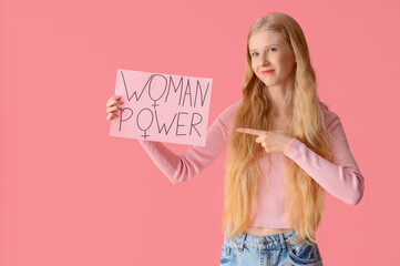 Young girl pointing at paper with text WOMAN POWER on pink background