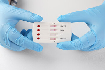 Doctor holding disposable multi-infection express test at white table, closeup