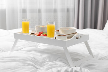 Tray with tasty breakfast on bed at home