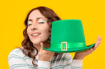 Happy woman with green hat on yellow background. St. Patrick's Day