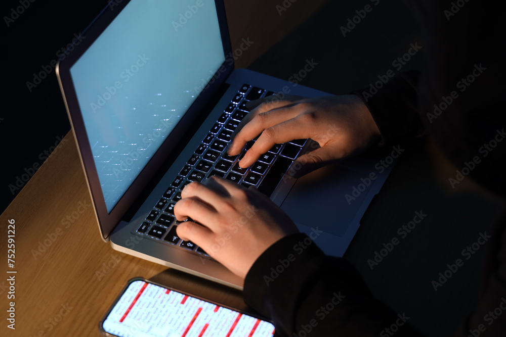 Poster hacker using laptop at table, closeup