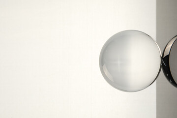 Transparent glass ball on light grey background. Space for text