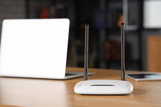 Modern wi-fi router on wooden table in room, closeup
