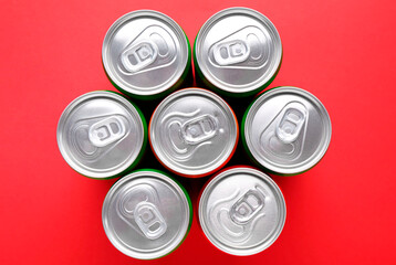 Energy drink in cans on red background, top view