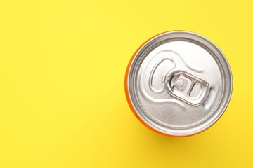 Energy drink in can on yellow background, top view. Space for text