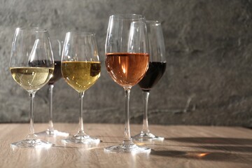 Different tasty wines in glasses on wooden table, space for text
