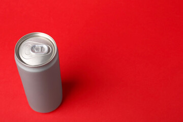 Energy drink in can on red background, space for text