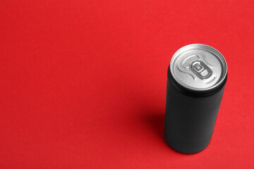 Energy drink in can on red background, space for text