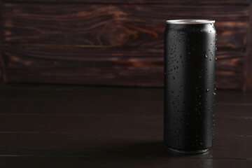 Energy drink in wet can on dark wooden table, space for text