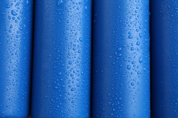 Energy drinks in wet cans as background, top view