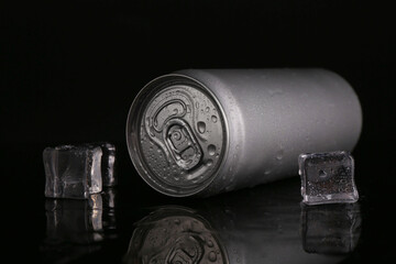 Energy drink in wet can and ice cubes on black background, closeup