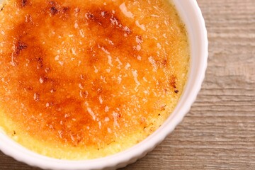 Delicious creme brulee in bowl on wooden table, top view
