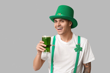 Tattooed young man in leprechaun's hat and with glass of beer on light background. St. Patrick's Day