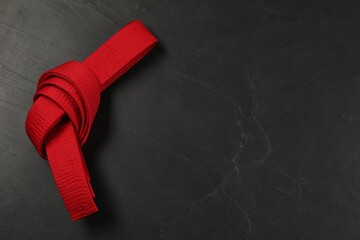 Red karate belt on gray background, top view. Space for text