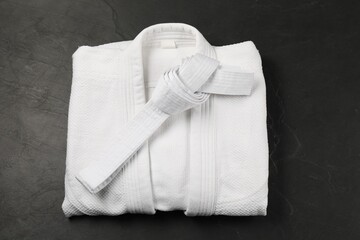White karate belt and kimono on gray background, top view