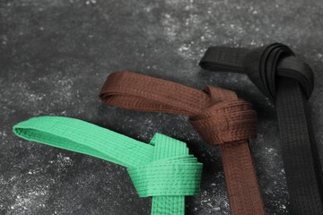 Colorful karate belts on gray background, flat lay