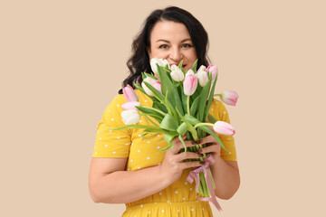 Happy mature woman with bouquet of beautiful tulips on beige background. International Women's Day