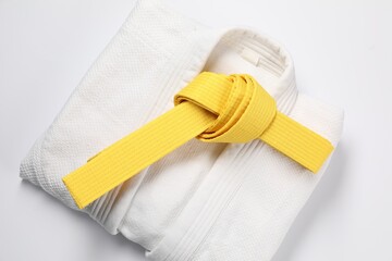 Yellow karate belt and kimono on white background, top view