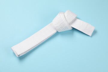 White karate belt on light blue background, top view