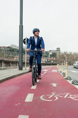 vertical portrait Businessman commuting to work on electric folding bike along red bike lane