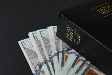 Holy Bible with money on black background, closeup