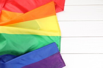 Rainbow LGBT flag on white wooden table, top view. Space for text
