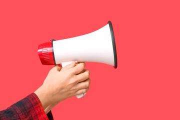 Female hands with megaphone on red background