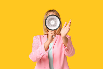 Mature woman with megaphone on yellow background