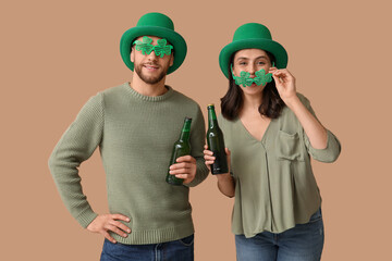 Beautiful young couple in leprechaun hats and decorative glasses in shape of clover with bottles of...