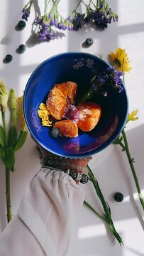 pov, woman's hands, fruit bowl, vibrant flowers, colorful mix, healthy eating, breakfast spread, brunch vibes, summer vibes, fresh produce, seasonal fruits, overflowing bowl, inviting, tempting, delic
