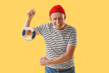 Mature sailor with small ring buoy on yellow background