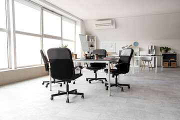 Interior of light conference hall with tables, window and armchairs