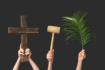 Female hands with wooden cross, mallet and palm leaf on dark background. Good Friday concept