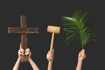 Female hands with wooden cross, mallet and palm leaf on dark background. Good Friday concept