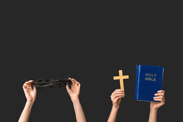 Female hands with crown of thorns, wooden cross and Holy Bible on dark background. Good Friday...