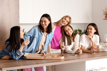 Young women with champagne and tasty pizza at Hen Party in kitchen