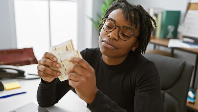 African woman examining danish currency in modern office, evoking themes of finance, diversity, and employment.