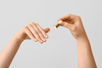 Female hands applying cuticle oil with pipette on white background, closeup