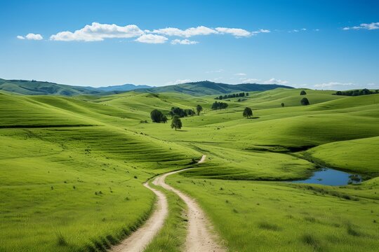 Countryside dirt road through lush green rolling hills landscape under blue sky