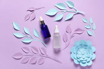 Bottles of cosmetic products, paper flowers and leaves on color background