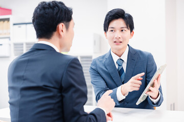 タブレット端末を使い窓口で説明をするビジネスマン