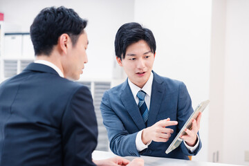 タブレット端末を使い窓口で説明をするビジネスマン