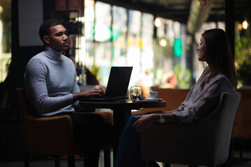 Friends at a cafe after work. Business colleagues working on laptop and drinking coffee in a restaurant..