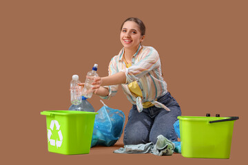 Young woman sorting trash on brown background