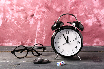 Composition with alarm clock and glasses on wooden table against pink background. Time management...