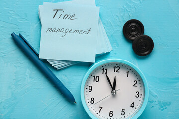 Paper with text TIME MANAGEMENT, alarm clock and pen on blue back ground. Time management concept. Top view